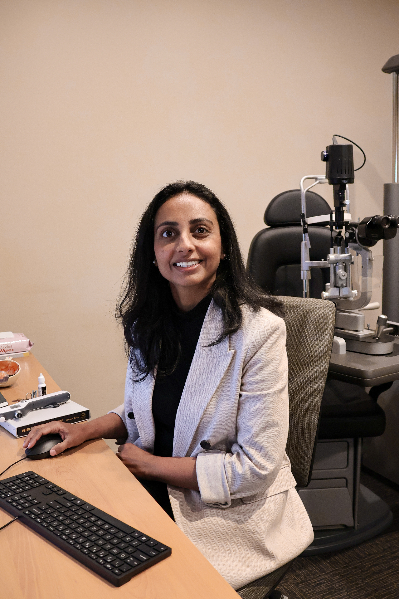 Dr Yachana Shah at her consulting desk beside a slit lamp